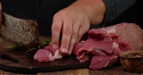 Adult Cutting Cubes of Raw Meat with Axe