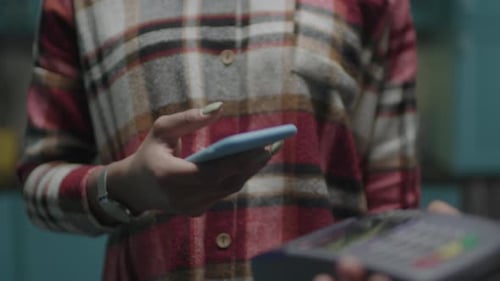 Female Hand Paying with Mobile Phone and Contactless Terminal