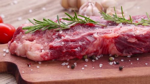 Raw Steak with Rosemary and Spices on Cutting Board