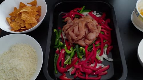 Seasoning Chopped Chicken Breast With Onion, Pepper And Chips On The Side - high angle shot, close u