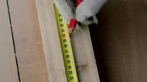 Worker Taking Measurement of Wooden Plank and Makes Notes with Carpenter Pencil