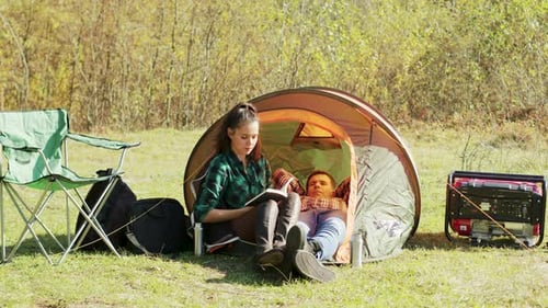 Woman Reading, Man Resting at Campsite