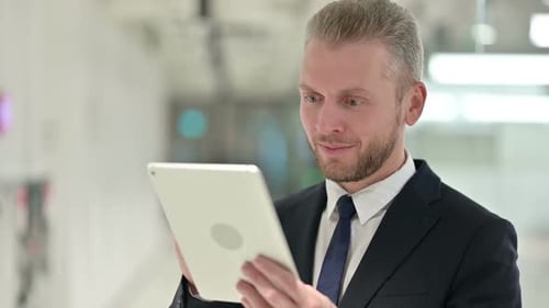 Successful Businessman Celebrating with Tablet in Office Building