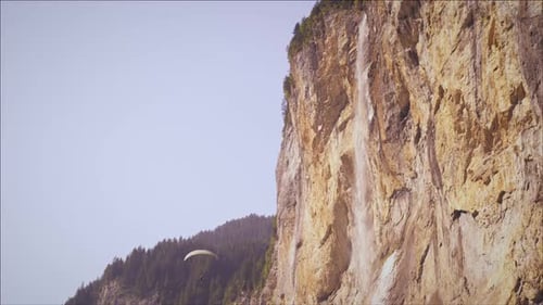 Paragliders Glide Near Cliffside Waterfall