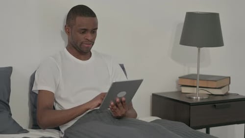 Young Adult Using Tablet in Bed