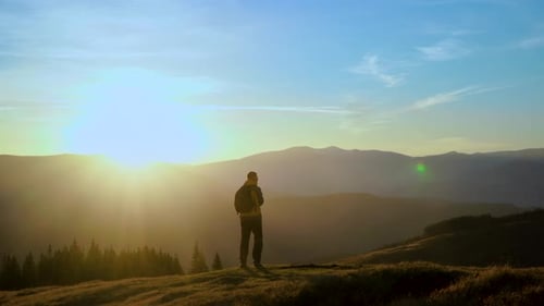 Man with Backpack Reaches Mountain Peak at Sunrise