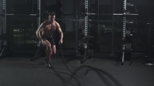 Athletic Man Performs Exercises with Battle Ropes Endurance Training in the Gym