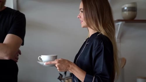 Woman Brings Coffee to Man in Kitchen