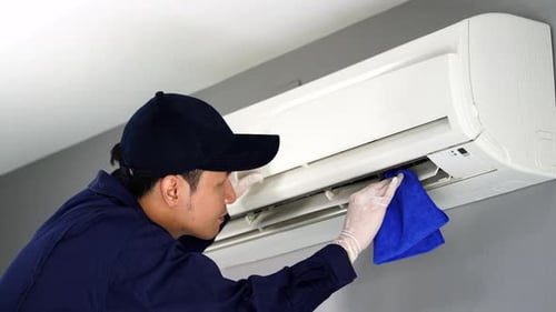 technician service cleaning the air conditioner with cloth