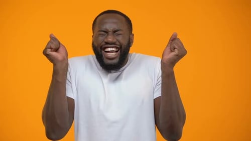 Junger afroamerikanischer Mann extrem glücklich, Lottogewinner, gelber Hintergrund