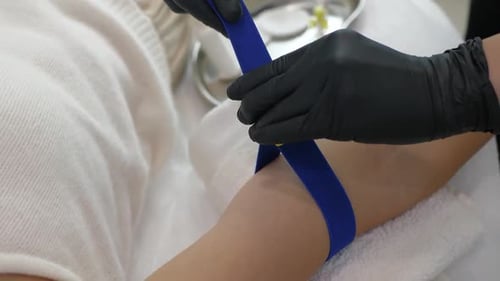 Healthcare Worker Securing Tourniquet on Patient's Arm