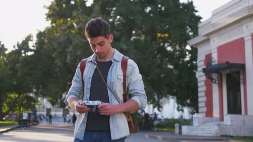 Young Attractive Handsome Man Tourist with Backpack Taking Photos on Vintage Camera in Old City