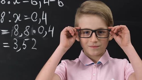 Boy with Glasses Smiling in Front of Chalkboard