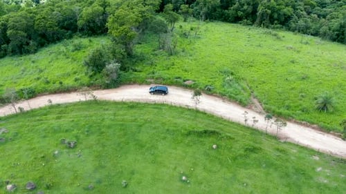 Aerial View of Car Driving Throuh a Small Dirt Road in the Middle of Green Tropical Valley.