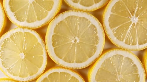Zeitlupe von frischen Zitronenscheiben auf gelbem Hintergrund