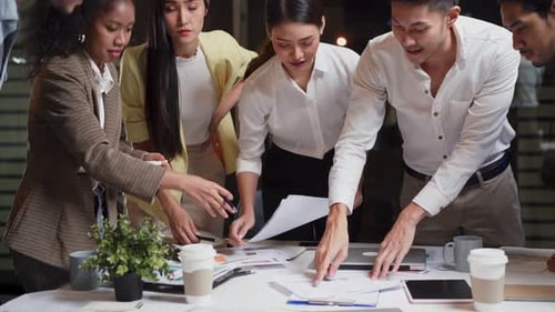 Asian young business people group brainstorming and working on discussion meeting in office at night