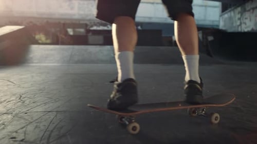 Sporty Man Training Skills on Skate Board at Sunset in Urban Skate Park