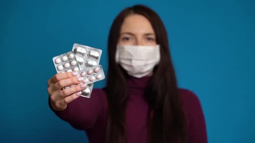 Woman Holding Pills While Wearing Face Mask