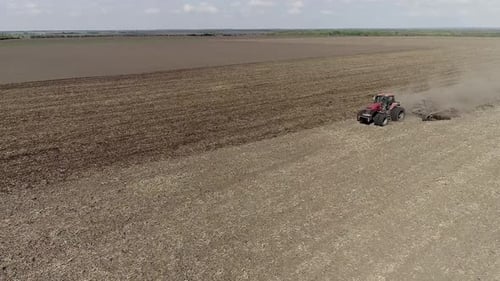 Tractor Cultivating Field at Spring