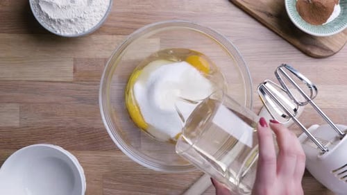 Female Hands Pour Oil into Cake Mix - Top Down Shot