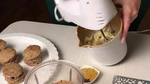 Frau macht Buttercreme. Für einen Kekskuchen mit Kekskrümeln. Gesamtplan.