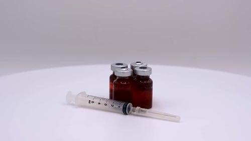 Impfstoffflasche mit roter Lösung mit Spritze