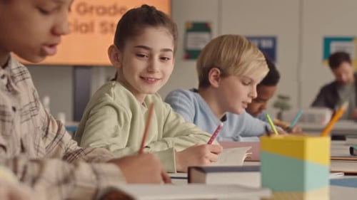 School Girl Looking at Classmate Copybook during Lesson
