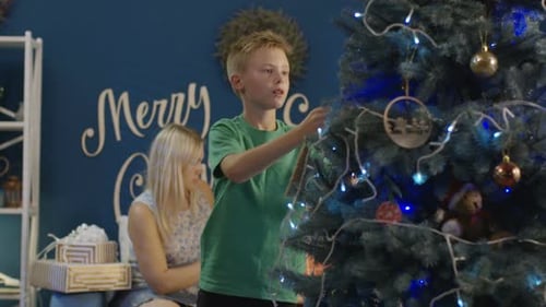 Boy Decorates Christmas Tree with Family