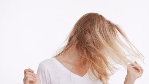 Young Beautiful Caucasian Blonde Girl Waving Hair and Head Smiling on White Background in Slowmotion