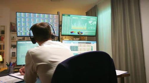 Broker with Headphones Checking Stock Market Graphs