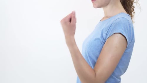 Woman Stands on White Background and Rubs Her Sore Elbow Side View