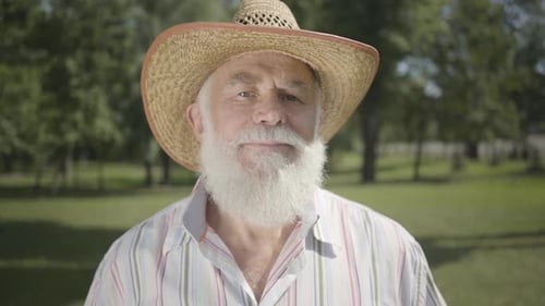 Portrait Old Grey-haired Bearded Man in Straw Hat Looking at Camera Smiling Standing in the Park