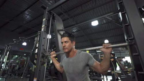 Portrait of strong caucasian man using fitness equipment, bar, doing exercise, working out