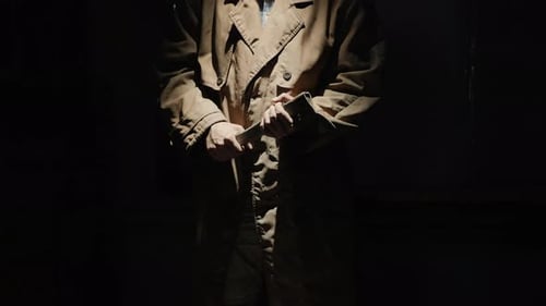 Sinister Figure with Knife in Darkened Room