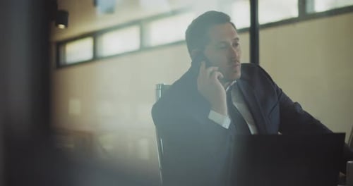 A businessman having a serious and stressful conversation over the phone while working at the office