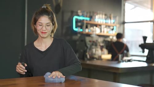 4K Asian woman coffee shop waitress using alcohol sanitizer cleaning counter bar