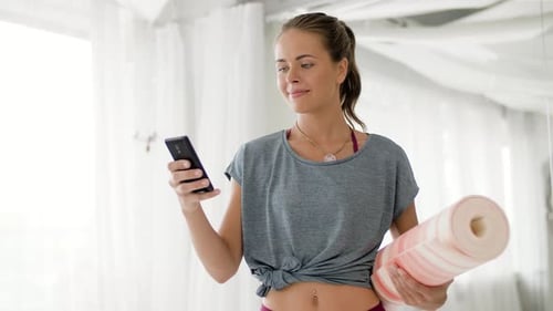 Happy Woman with Exercise Mat at Yoga Studio