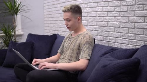 Young Man Using Laptop Computer on Couch at Home