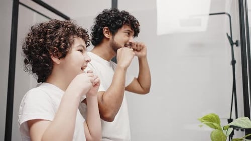 Father and Son Flossing Teeth Together in Bathroom