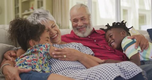 Grandparents and Grandchildren Cuddling on Couch Indoors