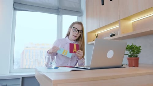 Young woman teacher shows pictures with the alphabet.Teaching children at school online