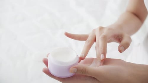 Woman Dips Finger In Moisturizing Cream