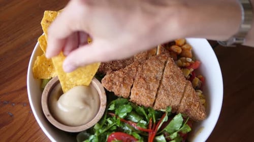 Dipping Chip into Crispy Chicken Salad Bowl