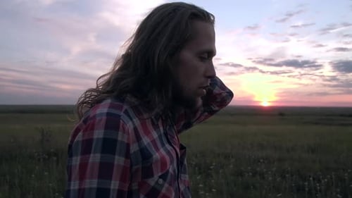 Contemplative Man with Long Hair in Sunset Field