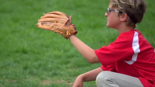 A boy practices playing catch on a little league baseball field.