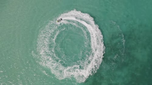 Aerial top view of jet ski or boat drawing a shape on sea ocean turquoise water. Adventure