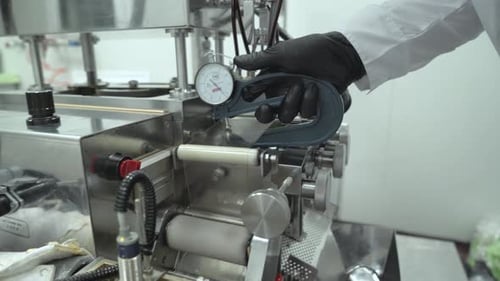 Wissenschaftler schieben Softgel-Kapseln mit Luftkompressorpistole Hand in schwarzem Handschuh
