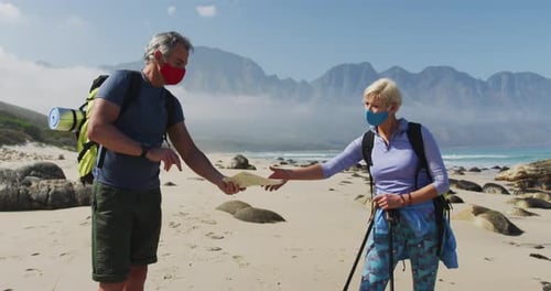 Couple Hiking on Beach Looking at Map Wearing Masks