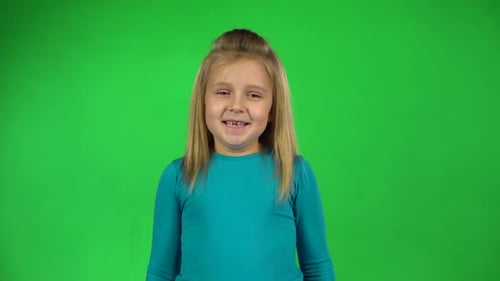 Portrait of Little Girl Posing Playfully on Green Background.