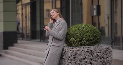 Stylish Woman Uses Phone and Earbuds in City